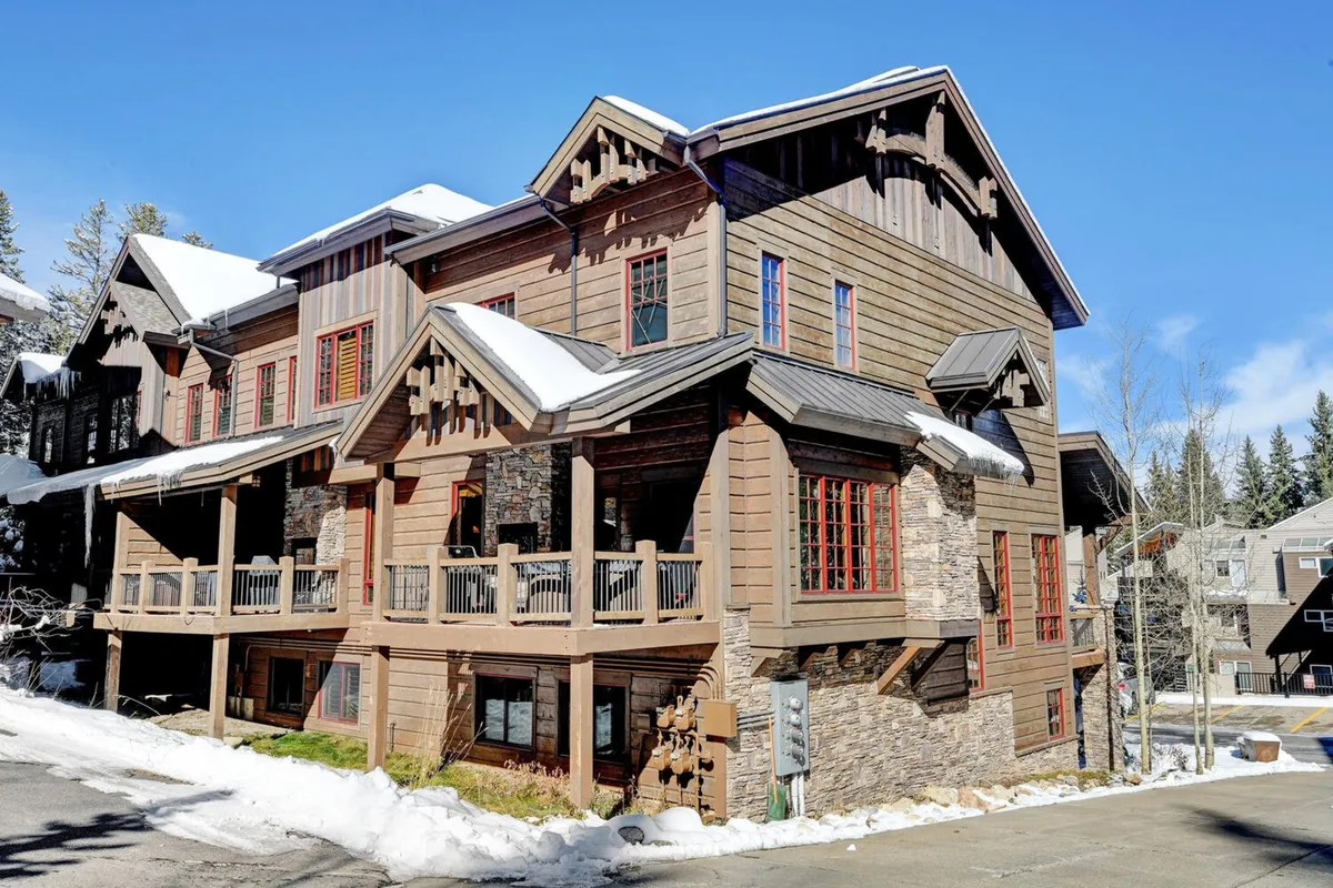 This image showcases a wooden balcony with stone accents and distinctive red window frames. The scene evokes moments of outdoor relaxation—perhaps enjoying nature views or gathering on the porch—with hints of the property’s architectural details and mountain ambiance.