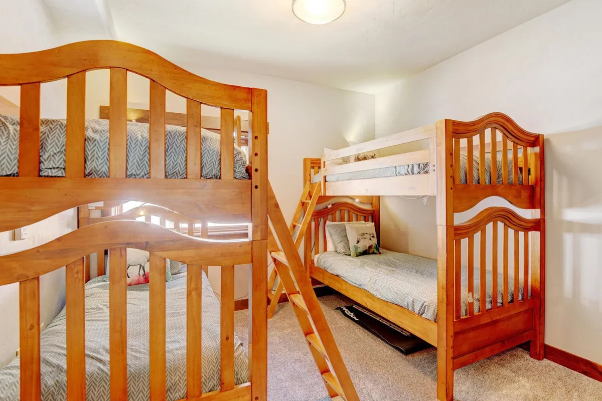 Playful bunk beds dressed in crisp linens, complete with a sturdy ladder and cozy bedding. The setup is perfect for children or teens, with a fun and inviting atmosphere that encourages both sleep and late-night storytelling.